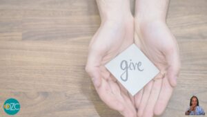 Mani aperte che offrono un biglietto con la parola ‘give’, simbolo dell’altruismo e del dare senza svuotarsi.”